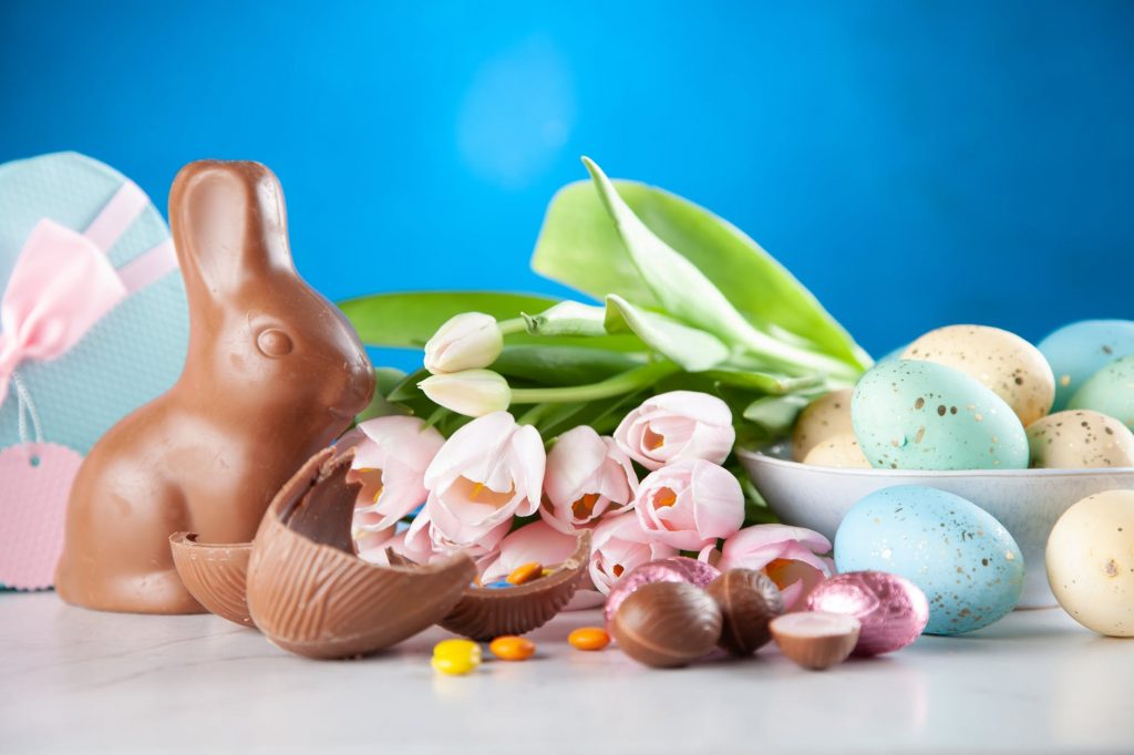 A chocolate Easter bunny alongside some tulips and fresh painted eggs. 